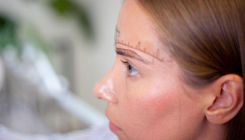 Side profile of a Blink Beauty Bar client with eyebrow mapping measurements marked above the brow in preparation for a microblading treatment in Buffalo, NY.