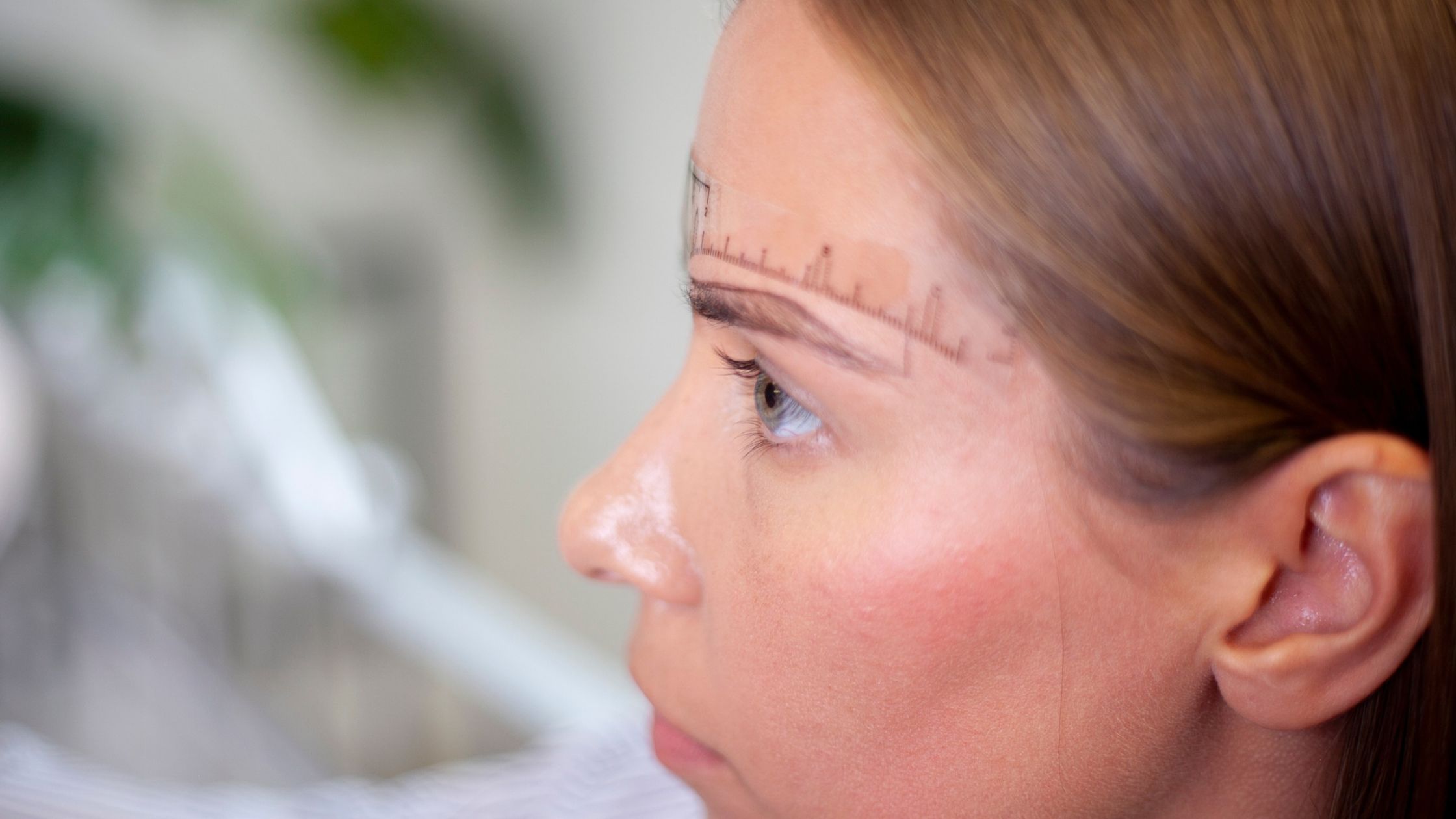 Side profile of a Blink Beauty Bar client with eyebrow mapping measurements marked above the brow in preparation for a microblading treatment in Buffalo, NY.