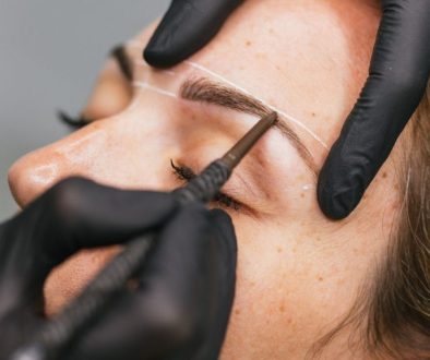 Close-up of eyebrow mapping and shaping with a cosmetic pencil before a microblading/ permanent makeup brow treatment.